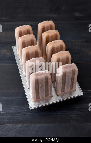 Eis am Stiel. Schokolade Hausgemachtes Sorbet in Kunststoff Form auf einem schwarzen Holz- hintergrund Kopie Platz für Text. Ansicht von oben Stockfoto