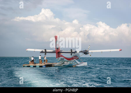 Malediven, Feb 10 2018 - ein Wasserflugzeug warten auf Touristen in einem offshore Holz Plattform in der Nähe des Hilton Hotel auf den Malediven. Blaues Wasser, bewölkter Himmel, Sonnig Stockfoto