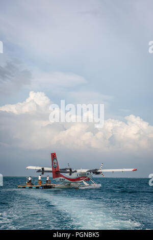 Malediven, Feb 10 2018 - ein Wasserflugzeug warten auf Touristen in einem offshore Holz Plattform in der Nähe des Hilton Hotel auf den Malediven. Blaues Wasser, bewölkter Himmel, Sonnig Stockfoto