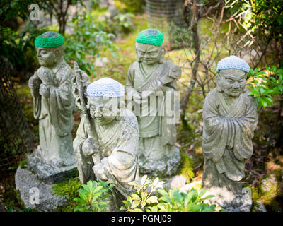 Statuen der ursprünglichen Anhänger Buddhas (Shaka Nyorai in Japan" genannt), mit gestrickten Mützen an Daisho-in Tempel (Daishoin Tempel), Miyajima, Japan. Stockfoto