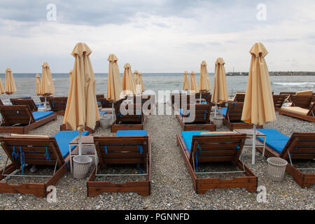 Sonnenschirme und leeren Liegestühlen an einem bewölkten Tag. Platamonas, Pieria, Mazedonien, Griechenland Stockfoto