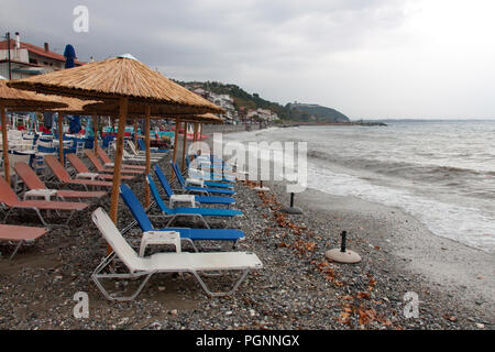 Sonnenschirme und leeren Liegestühlen an einem bewölkten Tag. Platamonas, Pieria, Mazedonien, Griechenland Stockfoto