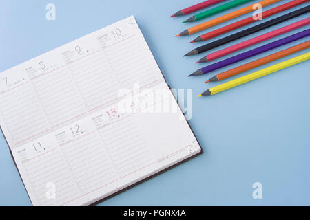 Kalender und Bunte Bleistifte in Winkel auf Pastell-blaue Hintergrund Tabelle isoliert. Platz für Text, flach Stil. Stockfoto