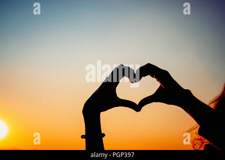 Silhouette frau Hände bilden Herzform mit Sonnenuntergang Stockfoto