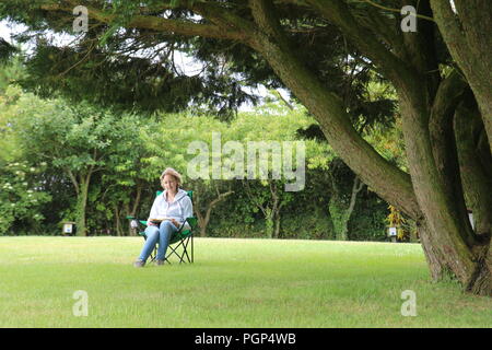 Junges Mädchen sitzen auf bequemen Stuhl im Park Stockfoto