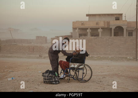 Das Krankenhaus von Gagjali, einem Vorort von Mosul, während der Offensive gegen ISIS. Ein Mann und sein Vater im Rollstuhl außerhalb des Krankenhauses. Gajali (IQ Stockfoto