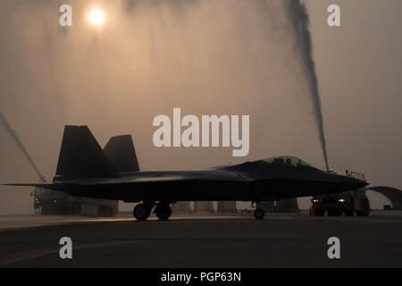 Generalleutnant Jeffrey L. Harrigian, US Air Forces Central Command Commander, wird feierlich mit Wasser aus Feuerwehrfahrzeuge gespritzt nach seinem letzten Flug dirigieren, oder "fini Flug, "in einem F-22 Raptor bei Al Dhafra Air Base, 8. August 2018. Da die kombinierte Kraft Air Component Commander, die Allgemeinen führt US-, Gelenk- und Koalition Flugbetrieb in der US Central Command der Verantwortung, eine 20-Nation, von Ägypten bis Afghanistan. (U.S. Air Force Foto von Tech. Sgt. Nieko Carzis) Stockfoto