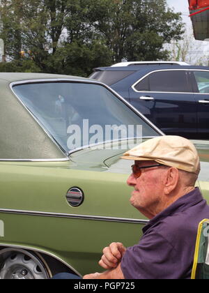 Ältere Mann mit einem Hut und Sonnenbrille an einem lokalen NJ Car Show von seiner ursprünglichen 1973 Dodge Dart. Stockfoto