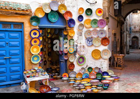 Marokko bunte Tonwaren auf Display für den Verkauf in einer malerischen Gasse. Platten aus vielen Farben an den Wänden hängen vor einem Geschäft. Ort: Essaouira Stockfoto