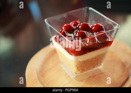 Himbeermarmelade süße Nachspeise, Käsekuchen, Kleinigkeit, Mousse Snack in einem Cocktail Glas auf einer hölzernen Fach Hintergrund. Festliches 2-in-1-Bäckerei in Glas mit Da Stockfoto