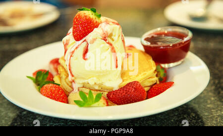 Frische rote Erdbeeren topping Vanilleeis auf Pfannkuchen gewürzt mit Erdbeersauce. Gesunde süße Nachspeise, Essen und Trinken, Stress Therapie. Stockfoto