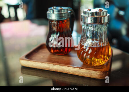 Glasflaschen in Holz- Fach auf Tisch, Haselnuss und Karamel flüssigen Sirup für Aromastoffe, Kaffee, Getränken und süßen Desserts Stockfoto