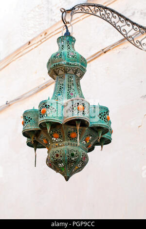 Marokkanische vintage durchbohrt Metall hanging lantern Exterieur Licht leuchte. Grüne Grünspan besetzt mit orange Cabochons. Ort: Essaouira, Marokko Stockfoto