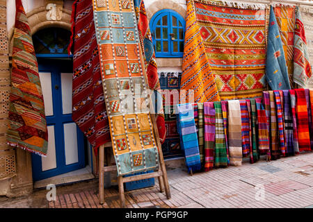 Marokkanische Shop mit bunten Teppichen und Teppichen auf Anzeige außen hängen an den Wänden. Ort: Essaouira, Marokko Stockfoto