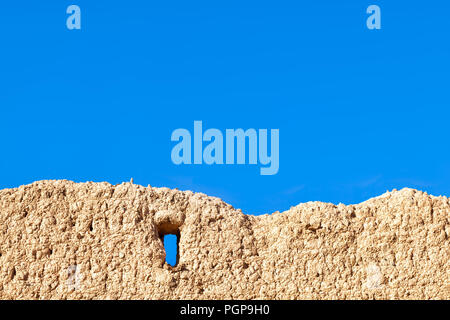 Marokko rustikalen Schlamm wand Detail mit Fenster Eröffnung gegen strahlend blauen Himmel. Kopieren Sie Platz. Stockfoto