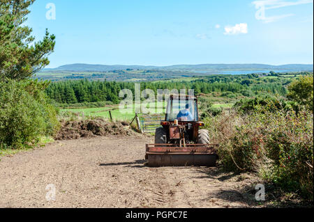 Landwirt brötchen Boden nach dem Einpflanzen Grassamen an einem sonnigen Tag in Ballydehob, West Cork, Irland mit kopieren. Stockfoto