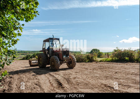 Landwirt brötchen Boden nach dem Einpflanzen Grassamen an einem sonnigen Tag in Ballydehob, West Cork, Irland mit kopieren. Stockfoto