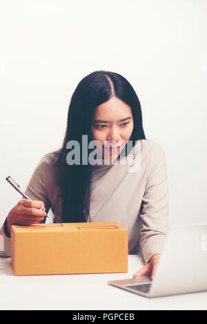 Start Small Business Owner arbeiten mit Computer am Arbeitsplatz. Freiberufliche Frau Verkäufer prüfen Produkt bestellen, Verpackung Waren zur Lieferung an den Kunden. O Stockfoto