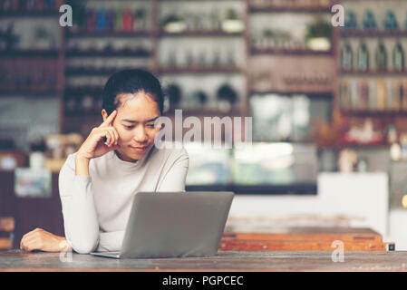 Eine attraktive Geschäftsfrau im mittleren Alter vor dem Laptop sitzen und die Verwaltung ihrer kleinen Unternehmen von zu Hause aus. Stockfoto