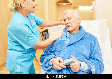 Kranker älterer Menschen in der Krankenpflege Bett ist gepflegt, von der Krankenschwester im Ruhestand home Stockfoto