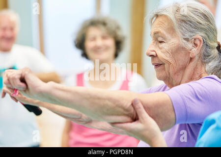 Senior erhält Hilfe mit einem elastischen Band Übung in die Pilates Klasse Stockfoto