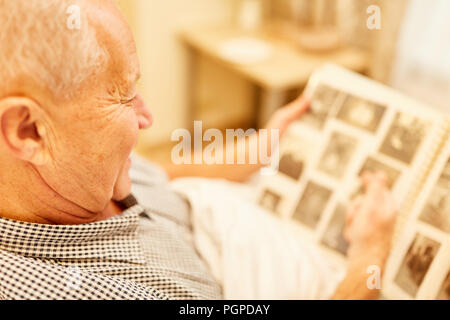 Alte Menschen mit Demenz oder Alzheimer in Pflegeheim betrachtet ein Foto album Stockfoto