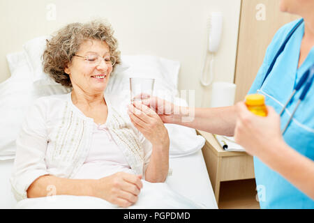 Caregiver gibt alte Frau Tablet mit oralen Wasser in den Ruhestand home Stockfoto