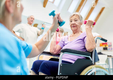 Ältere Frau im Rollstuhl, Reha Training mit Kurzhanteln nach Schlaganfall Stockfoto