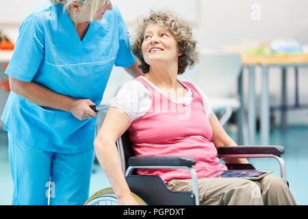 Krankenschwester Pflege für ältere Frau im Rollstuhl nach Schlaganfall in der Reha Klinik Stockfoto