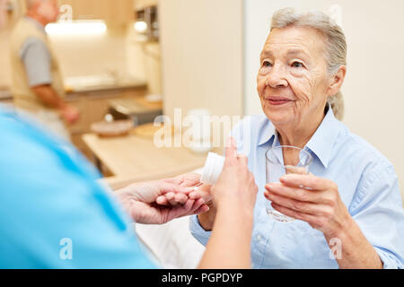 Caregiver gibt ältere Frau als Patient Tabletten bei betreuten Senioren apartment Stockfoto