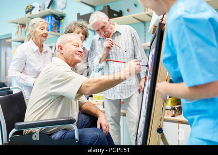 Gruppe von Seniorinnen und Senioren mit Demenz Farben zusammen in der kreativen Malerei Therapie Stockfoto