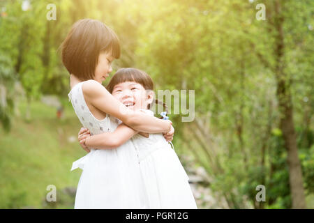 Schwestern spielen und schmusen im Garden Park. Asiatische Familie im Freien portrait. Stockfoto