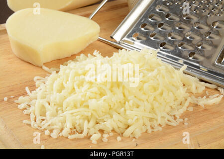 Geriebenen Mozzarella-Käse auf ein Schneidebrett mit einer Reibe Stockfoto