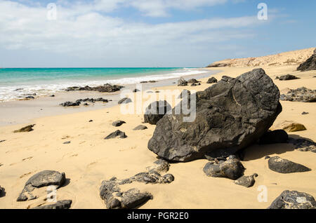 Große schwarze Vulkangestein an einem tropischen Strand Stockfoto