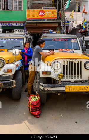 SIKKIM, INDIEN - Mar 13, 2017: Unbekannter indischer Mann und Frau stehen zwischen zwei Autos. Stockfoto