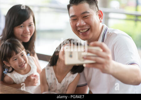 Gerne asiatische Familie selfie mit Smart Phone im Cafe. Lebensstil im Freien mit natürlichem Licht. Stockfoto