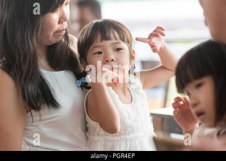 Candid Schießen von Menschen in der Cafeteria. Kleines Mädchen mit verschiedenen Gesichts Ausdruck. Asiatische Familie Lebensstil im Freien mit natürlichem Licht. Stockfoto