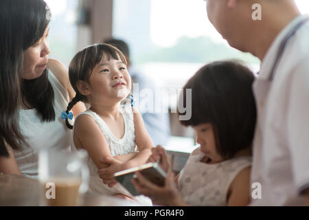 Candid Schießen von Menschen in der Cafeteria. Kleines Mädchen mit verschiedenen Gesichts Ausdruck. Asiatische Familie Lebensstil im Freien mit natürlichem Licht. Stockfoto