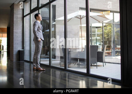 Zuversichtlich Geschäftsmann auf der Suche durch das Fenster Stockfoto
