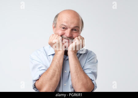 Portrait von niedlichen kahlen Kaukasier Männlich, Hände auf die Wangen, lächelnd und sah auf die Kamera Stockfoto