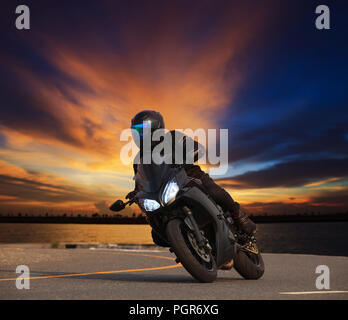 junger Mann Reiten big-Bike Motorrad schiefe Kurve auf Autobahnen Asphaltstraße gegen schönen düsteren Himmel Verwendung als Menschen Abenteuer Sport Freizeit Thema Stockfoto