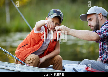 Vater mit seinem Sohn sitzen im Boot und kleine Fische Stockfoto