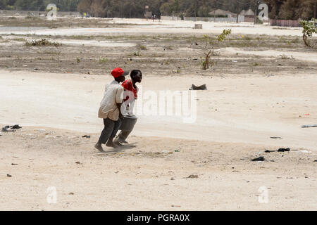 LAC ROSE reg., SENEGAL - Apr 27, 2017: Unbekannter senegalesischen Jungen schwer tragen Becken am Strand. Noch viele Menschen im Senegal leben in Armut Stockfoto