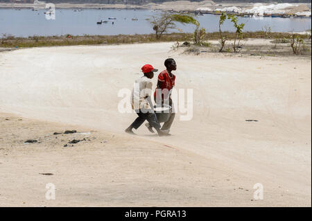 LAC ROSE reg., SENEGAL - Apr 27, 2017: Unbekannter senegalesischen Jungen schwer tragen Becken am Strand. Noch viele Menschen im Senegal leben in Armut Stockfoto