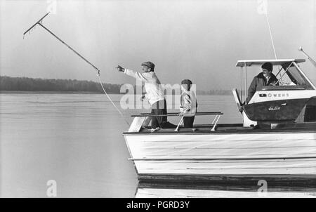 VANCOUVER, Washington, USA - November 24, 1982: Suche nach Columbia River für D. B. Cooper bleibt und Geld. Richard Tosaw wirft Baggerarbeiten Werkzeug aus dem Boot. An November 24, 1971, Cooper entführten Northwest Airlines Jet in der Nähe von Portland, Oregon und Fallschirm mit $ 200.000 in bar er von Fluggesellschaft erpresst. Brian Ingram (Mitte), die 11-jährige Junge, der $ 5.800 markierte $ 20 Rechnungen im Februar 1980 gefunden, schaut an. Stockfoto