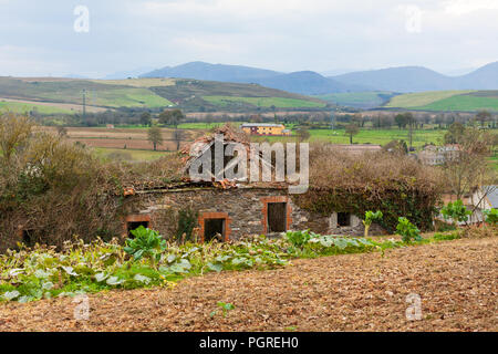 Kleine ländliche Haus mit grünen Hügeln im Hintergrund in Asturien, Spanien Stockfoto