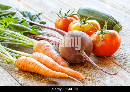 Karotten, rote Beete, Tomaten und Zucchini einfach nur im Garten auf Holzbrettern abgeholt Stockfoto
