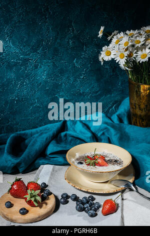 Chia Samen Pudding in Schüssel mit Erdbeeren und Blaubeeren auf Tisch Stockfoto