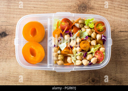 Lunch Box mit gesunden Lebensmitteln bereit zu essen. Kichererbsen Salat auf Holztisch. Ansicht von oben Stockfoto