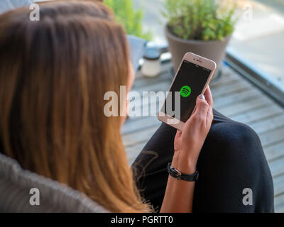 Stockholm, Schweden, 14. Juni 2018: Frauen, die ein Smartphone oder Handy mit Spotify Musik App laden. Ansicht von der Rückseite, selektive konzentrieren. Stockfoto